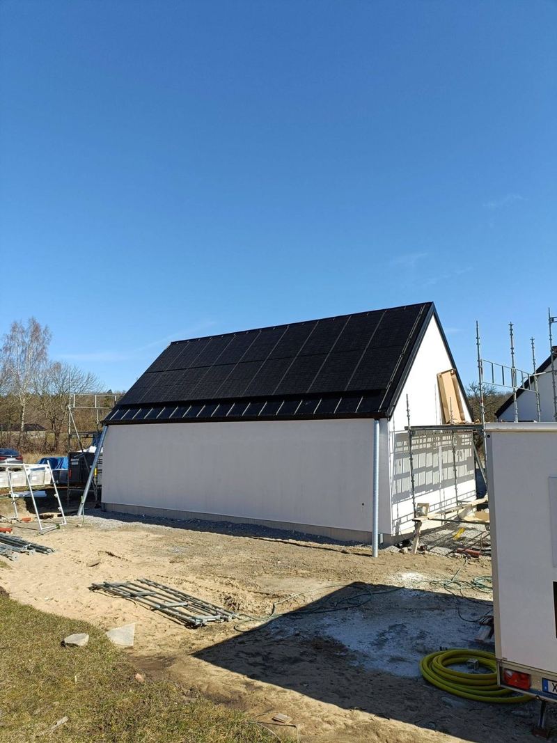 Svarta solceller på ett garage med falsat plåttak